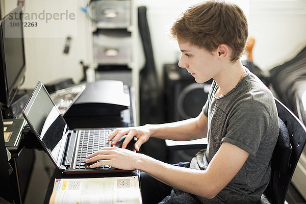 Teenager Jungen schreiben auf dem Laptop