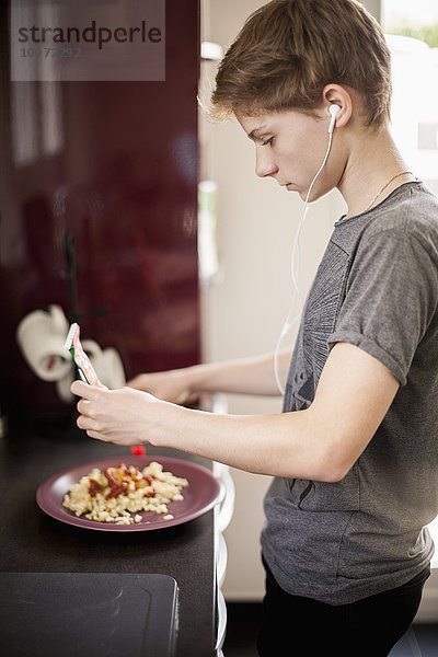 Teenager Junge hört Musik mit Frühstück