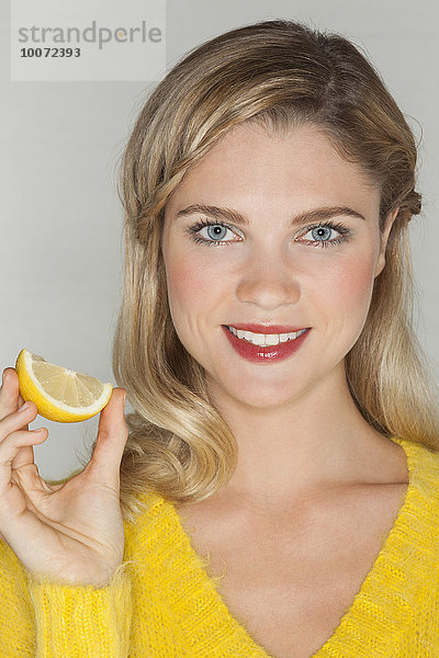 Porträt einer schönen Frau mit einem Stück Orange und lächelndem Gesicht