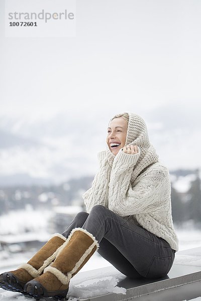 Schöne Frau sitzt auf einem Felsvorsprung und lächelt  Crans-Montana  Schweizer Alpen  Schweiz