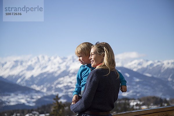 Frau trägt ihren Sohn mit schneebedecktem Berg im Hintergrund  Crans-Montana  Schweizer Alpen  Schweiz