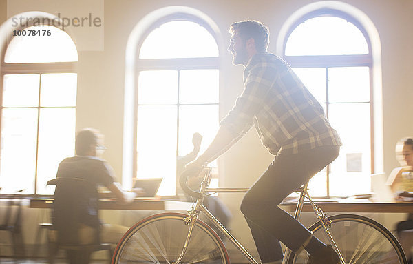 Lässiger Geschäftsmann auf dem Fahrrad im sonnigen Büro