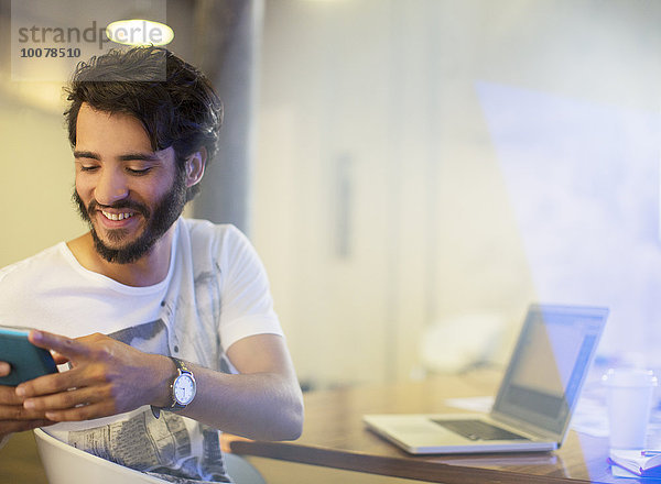 Lächelnder Geschäftsmann SMS mit Handy im Büro