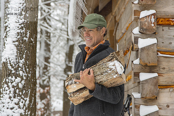 Feuerholz nahe Mann tragen Schnee mischen Mixed Schuppen