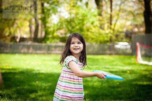 Junges Mädchen wirft Frisbee in den Garten