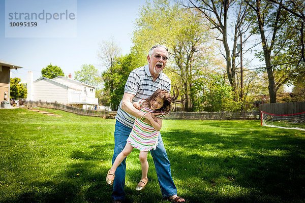 Großvater und Enkelin beim Spielen im Garten
