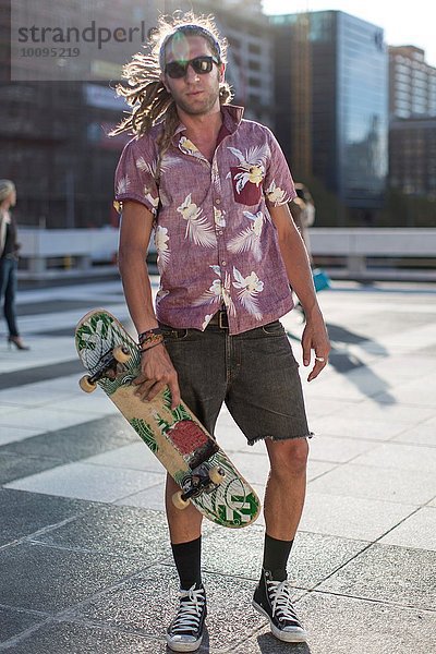 Junger Mann mit Skateboard  Portrait