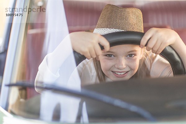 Junges Mädchen im Fahrersitz des Autos  hält Lenkrad  lächelt