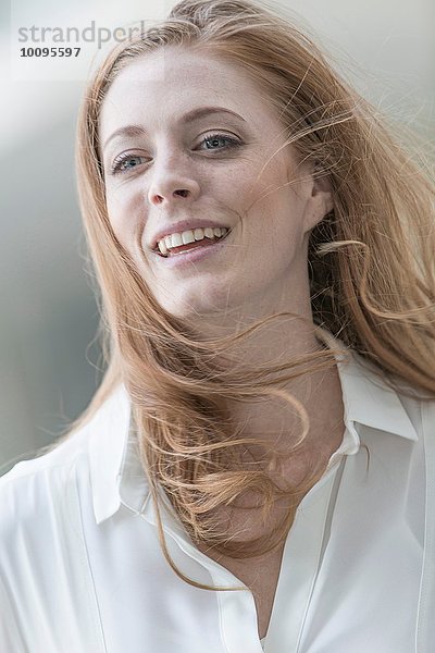 Porträt einer schönen jungen Frau mit langen roten  windgepeitschten Haaren