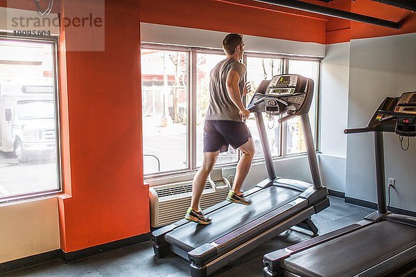 Erschöpfter erwachsener Mann  der auf dem Laufband bergauf rennt.