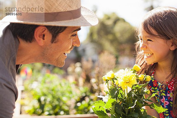 Mittelgroßer Mann und Tochter mit gelber Blütenpflanze im Gemeinschaftsgarten