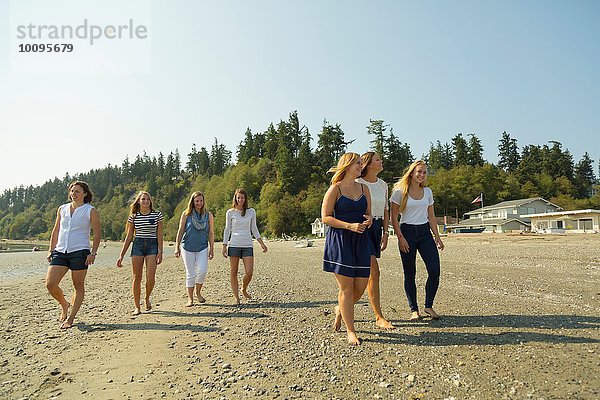 Familie von Schwestern und Cousins  die am Strand spazieren gehen.