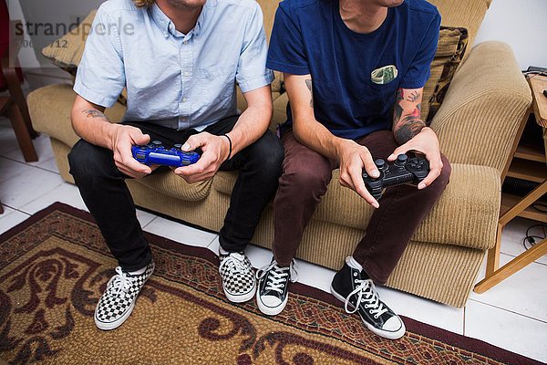 Zwei junge Männer sitzen auf dem Sofa  spielen Videospiel  niedriger Abschnitt