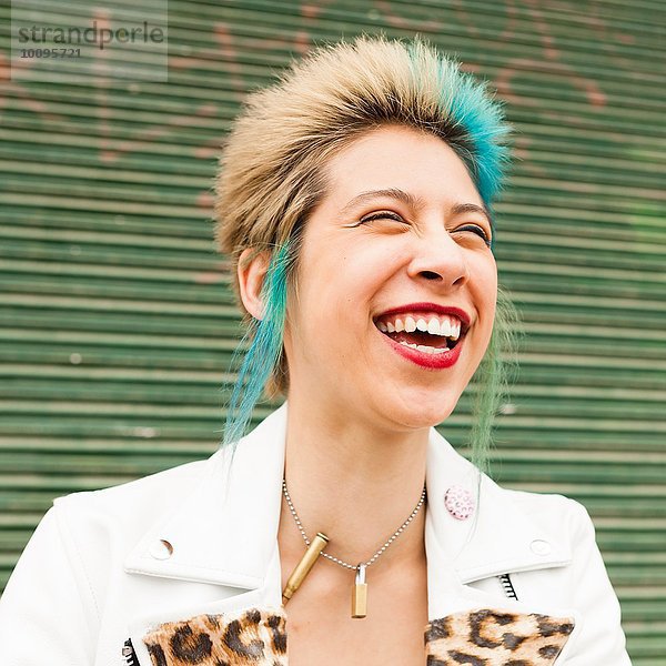 Porträt einer jungen Frau mit buntem Haar  lachend  im Freien