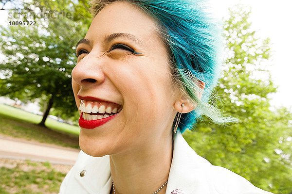 Porträt einer jungen Frau mit buntem Haar  lachend  im Freien