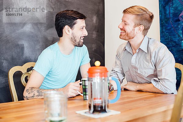 Männliches Paar am Tisch sitzend  Kaffee trinkend