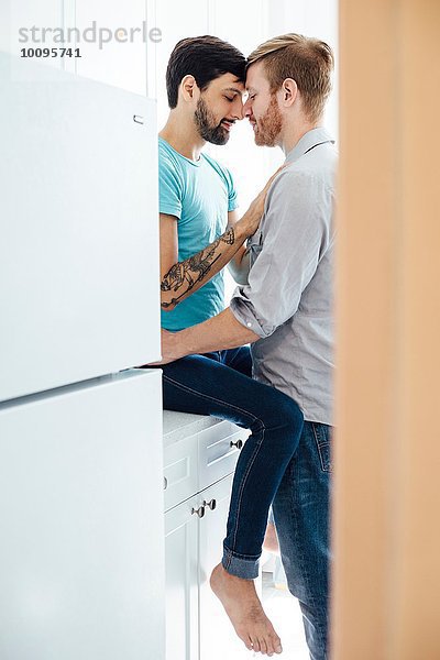 Männliches Paar in der Küche  von Angesicht zu Angesicht  umarmend
