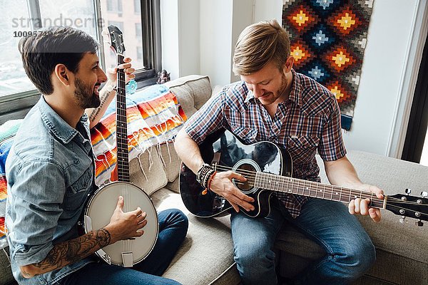 Männliches Paar zu Hause  Gitarre und Banjo spielen  lachend