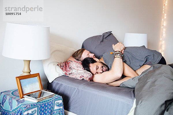 Männliches Paar auf dem Bett  umarmend  lächelnd