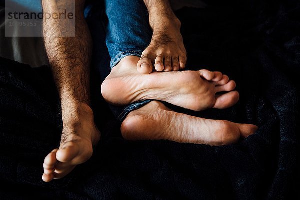 Männliches Paar liegt zusammen und konzentriert sich auf die Füße.