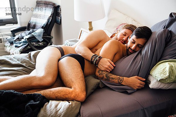 Männliches Paar  teilweise bekleidet  zusammen auf dem Bett liegend  schlafend