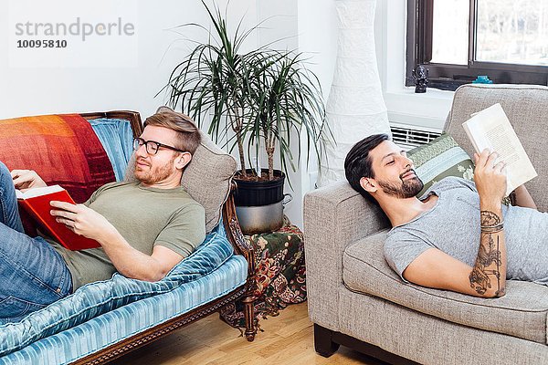Männliches Paar liest zu Hause