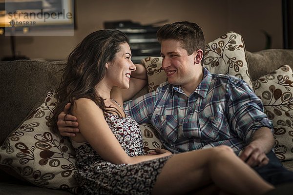 Romantisches junges Paar auf dem Wohnzimmersofa liegend