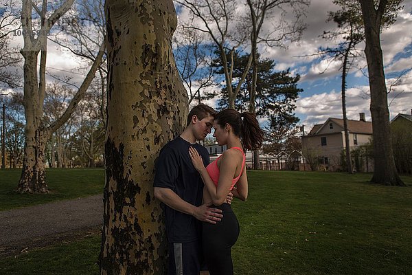 Romantisches junges  sportliches Paar  das sich in der Abenddämmerung im Park umarmt.