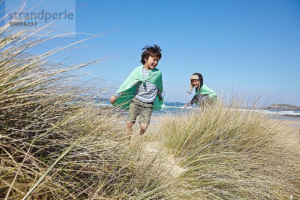 Zwei Jungen in Kostümen  die am Strand spielen