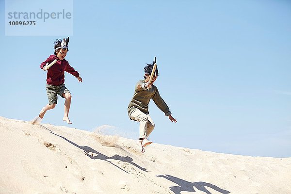 Zwei Jungen in Kostümen  die auf Sand spielen