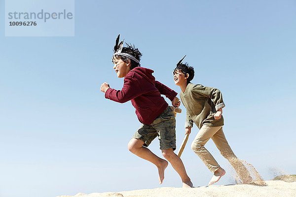 Zwei Jungen in Kostümen  die auf Sand spielen