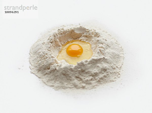 Backzubereitung mit rohem Ei in der Mitte des Mehlstapels