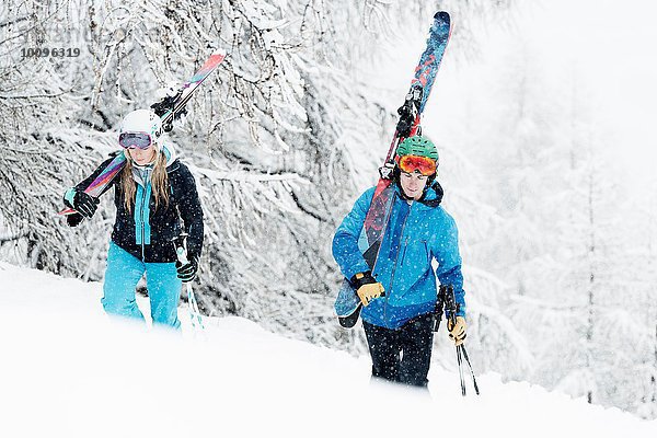 Mann und Frau mit Skiern im Schnee unterwegs