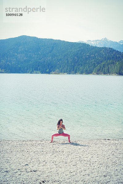 Mittlere erwachsene Frau  am See  in Yogastellung