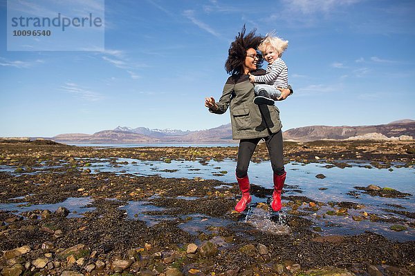 Mutter mit Sohn beim Springen in Loch Eishort  Isle of Skye  Hebrides  Schottland