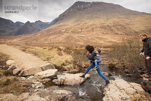 Frau springt über Bach  Fairy Pools  bei Glenbrittle  Isle of Skye  Hebrides  Schottland