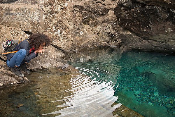 Frau trinkt Wasser aus hohlen Händen  Fairy Pools  Isle of Skye  Hebrides  Schottland