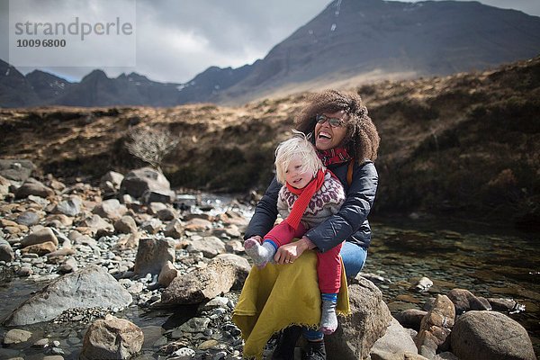 Mutter und Sohn sitzen auf Felsen  Fairy Pools  Isle of Skye  Hebrides  Schottland