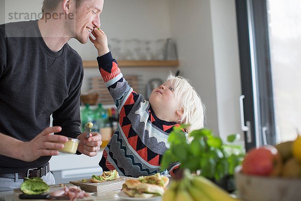 Junge berührt Vaters Gesicht in der Küche