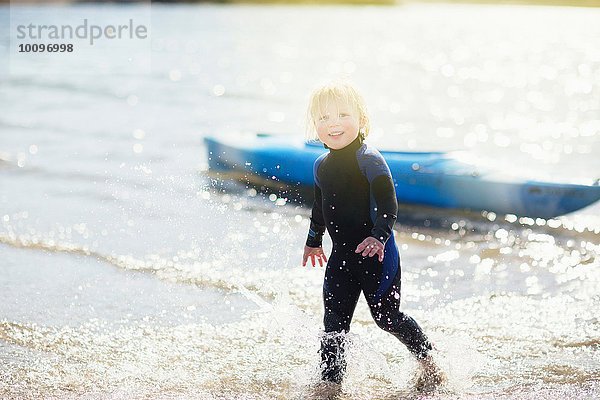 Junge im Wasser mit Kanu im Hintergrund