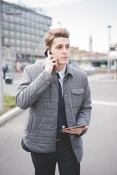 Portrait eines jungen Geschäftsmannes mit digitalem Tablett und Handy.