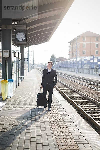 Porträt eines jungen Geschäftsmannes  der am Bahnsteig entlang läuft.