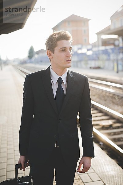Portrait eines jungen Geschäftsmannes  der auf dem Bahnsteig steht.