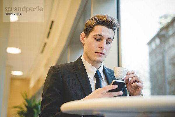 Porträt eines jungen Geschäftsmannes  der im Cafe sitzt  mit digitalem Tablett und Handy.