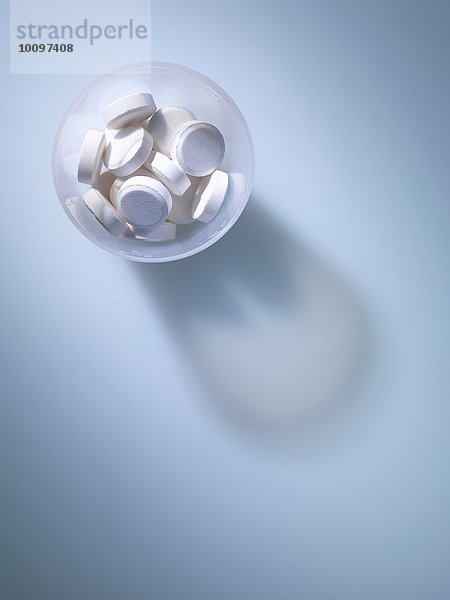 Draufsicht auf weiße Tabletten im Kunststoff-Messbecher