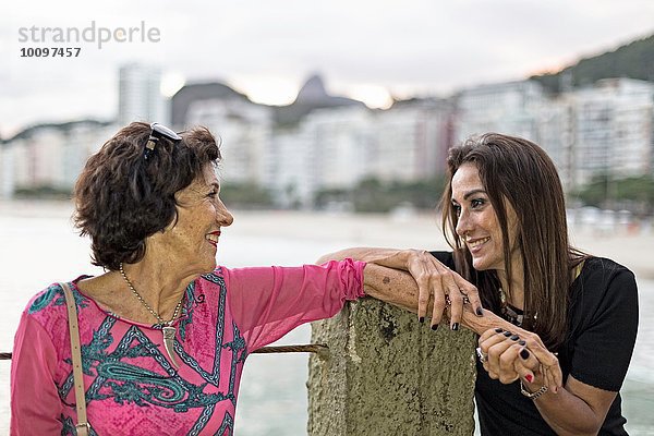 Reife Frau hält die Hand ihrer Mutter am Strand  Copacabana  Rio de Janeiro  Brasilien