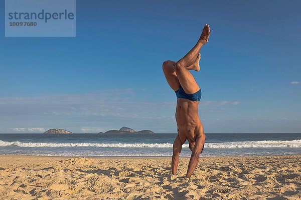 Mittlerer Erwachsener Mann beim Handstand am Strand  Rio de Janeiro  Brasilien