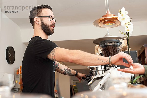 Cafe Kellner  der dem Kunden die Münzen von hinten überreicht.