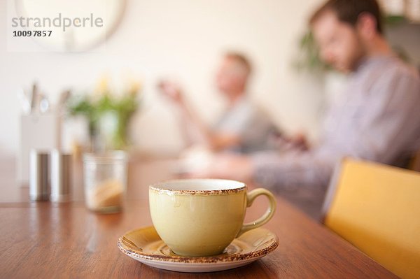 Tasse auf dem Tisch und Leute im Hintergrund in einem Cafe