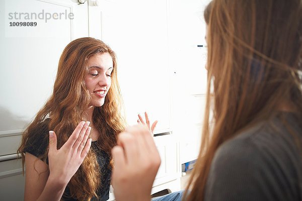 Zwei Teenager-Mädchen im Schlafzimmer helfen sich gegenseitig beim Schminken.